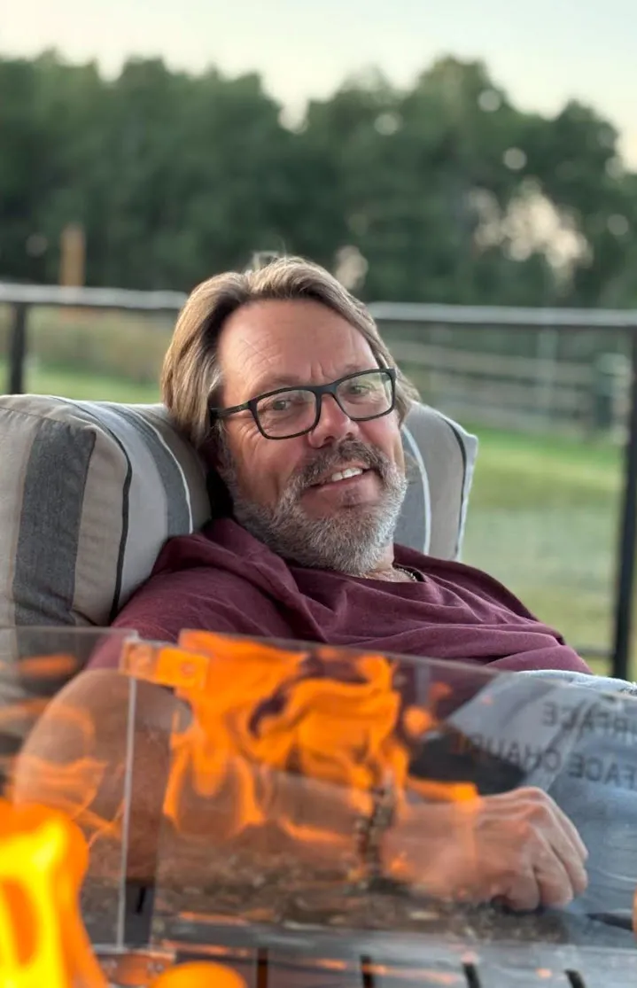 Mark Banham seated outdoors in front of a fire